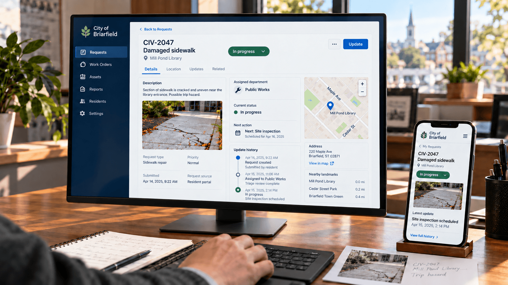 Concept study: a city service-request screen on a desktop monitor and a phone, showing a damaged-sidewalk request assigned to Public Works with a map, status, and update history.