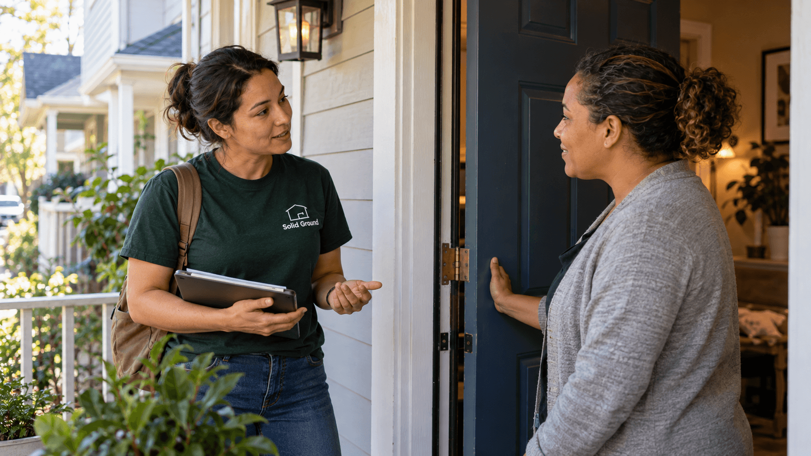 A Solid Ground staff member speaking with a neighbor at their front door